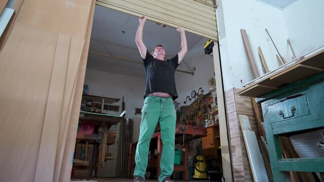 Local Business Owner Opening Up Shop, Sliding Garage Door Of Carpentry Store