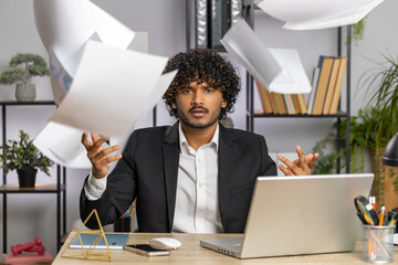 Stressed indian businessman working looking at unpaid bank debt bills, doing paperwork, planning...