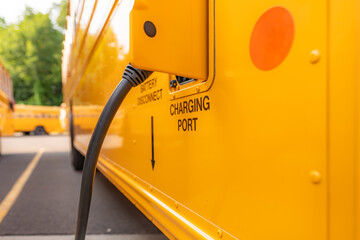 Photo of a yellow electric school bus plugged in at a charging station.