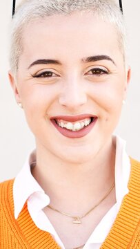 Vertical Portrait of young woman looking at camera. Close up face of cheerful girl smiling outdoor. Confident beautiful happy empowered entrepreneur shaved hair lady. High quality 4k footage