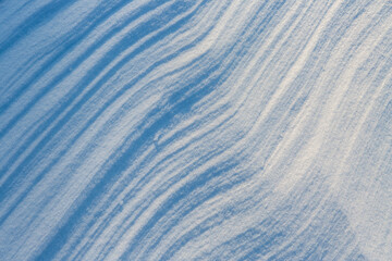 Fototapeta na wymiar Beautiful winter background with snowy ground. Natural snow texture. Wind sculpted patterns on snow surface.