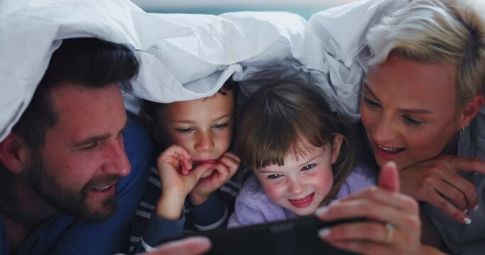 Parents, children and night with tablet, blanket and happy together for meme, movie and comedy show in family home. Mother, father and kids with touchscreen, funny video and relax in bedroom at house