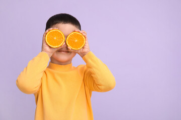 Cute little boy with oranges on lilac background