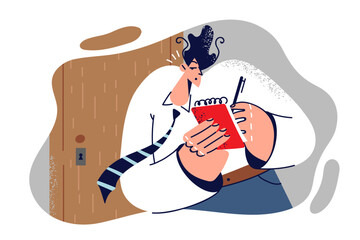 Man is spying on competitors standing at door and writing down overheard secrets in notebook