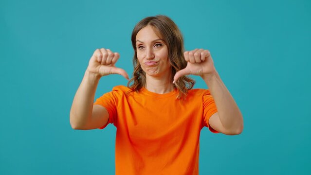 Dissatisfied lady purses lips and frowns showing thumbs-down