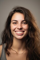 Naklejka premium headshot of a happy young woman looking at the camera on gray background