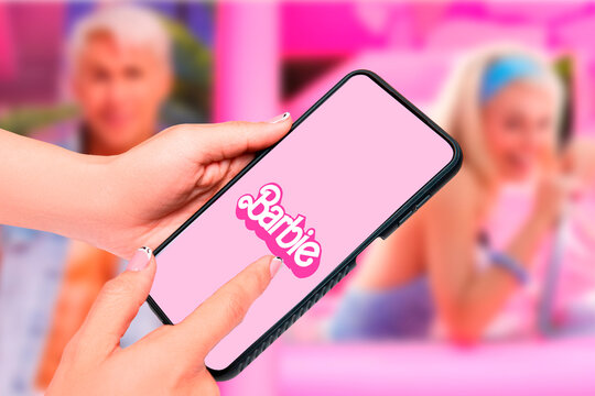 Buenos Aires, Argentina; 08-03-2023: Barbie the movie. Thematic horizontal background of woman's hands holding a cell phone that represents the success and fury for the Barbie movie.