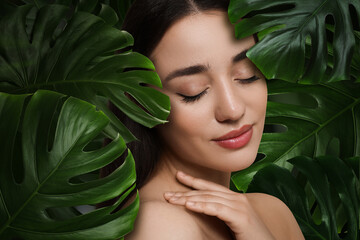 Beautiful young woman feeling harmony while enjoying nature. Girl surrounded by green leaves