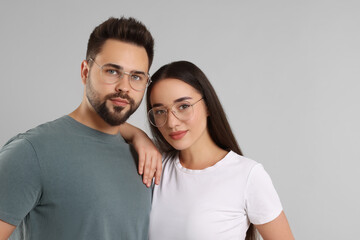 Beautiful couple wearing glasses on light gray background, space for text
