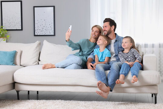 Happy family taking selfie together on sofa at home