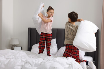Brother and sister having pillow fight while changing bed linens in bedroom