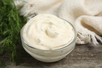 Tasty creamy sauce and fresh dill on wooden table, closeup