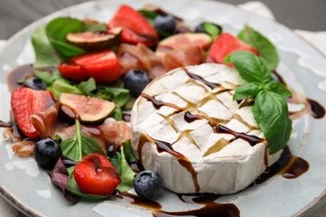 Delicious salad with brie cheese, berries and balsamic vinegar on plate, closeup