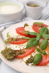 Plate of delicious Caprese salad with pesto sauce on table, closeup
