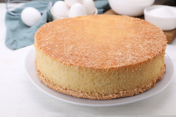 Plate with delicious sponge cake on white wooden table, closeup