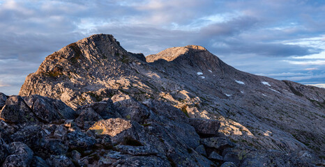 Sun setting over Breitinden and Tortenviktinden from smaltinden, Melöy, Norway during a summer thunderstorm. Hiking in Helgeland. Topptur norska fjell. Fjelltur. Dramatic mountain weather. Sunset dusk