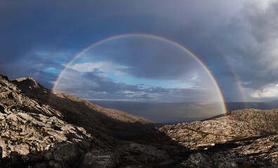 Panorama of an elusive double rainbow on a Norwegian mountain. Regnbåge over Smaltind, Breitind, Luröy, Helgeland, Nordnorge. Mountain rainbow. Dramatic storm light. Norway weather. High resolution. 
