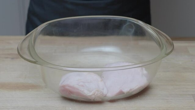 chicken thigs and legs are layered in  a glass casserole dish for marinating