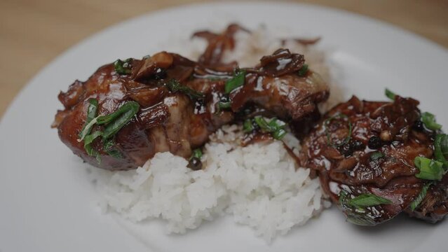close up shot of chicken adobo dish and dark gravy poured over chicken legs on fresh jasmin rice