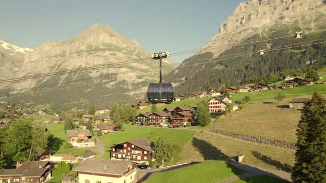 dolly sideways left to right following an ascending cabin of tricable car system Eiger Express in Grindelwald in fantastic evening light with clear sky