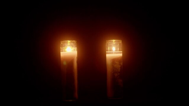 Two candles flickering in front of a black background void