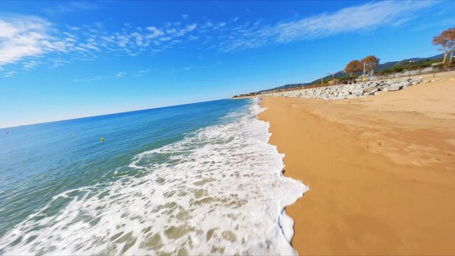 FPV aerial drone flying fast along a picturesque Mediterranean beach along the coast of Spain.