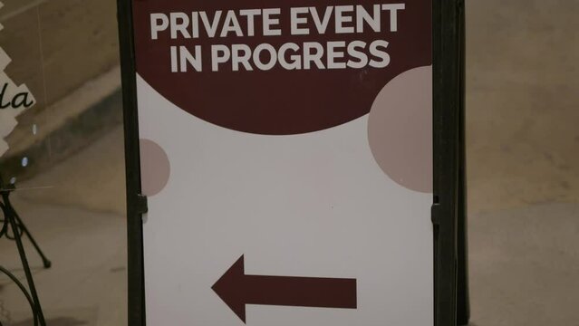 Wedding Day stock clip of private event in progress sign welcoming guests to venue on black A Frame with arrow pointing left with room for copy. Slight handheld styled intentional camera movement.