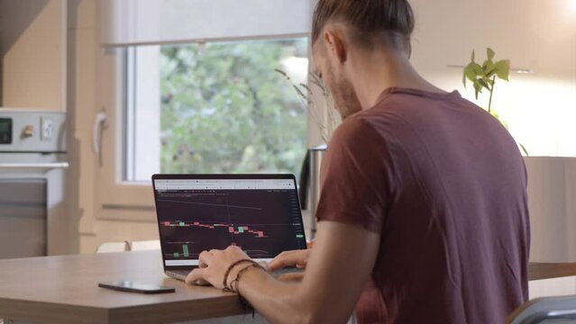 Slow motion shot of a man checking stock bar charts and pumping his fists in happiness