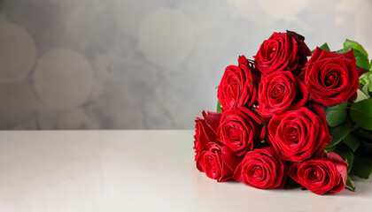 Luxury bouquet of fresh red roses on light table, space for text