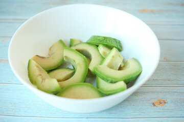  slice of avocado in a bowl on wooden table 