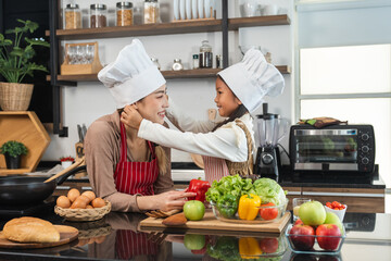 Happy moment asian mother and daughter cooking breakfast salad in the kitchen. Mom and daughter asian family having fun preparing healthy food vegetable. Positive parent and kid nice relationship