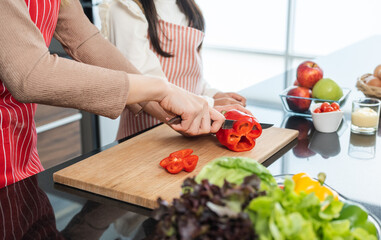Happy moment asian mother and daughter cooking breakfast salad in the kitchen. Mom and daughter asian family having fun preparing healthy food vegetable. Positive parent and kid nice relationship