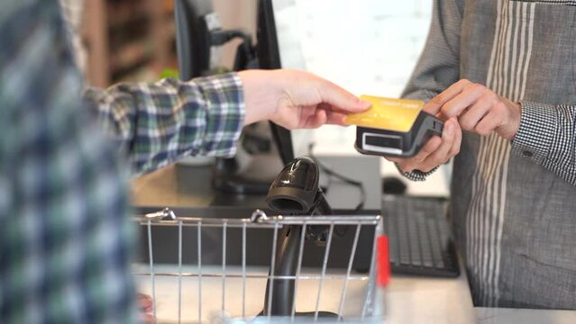 Caucasian women buying some food and vegetable in city grocery store and making a checkout process at cashier counter.