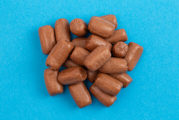 A Pile of Freeze Dried Chocolate Candy Rolls Isolated on a Blue Background