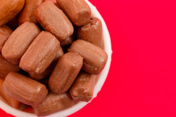 Fototapeta premium Pile of Freeze Dried Chocolate Candy Rolls Isolated on a Red Background
