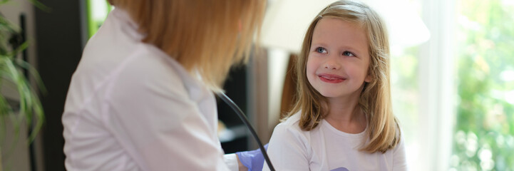 Young female patient smiles at doctor at medical examination.