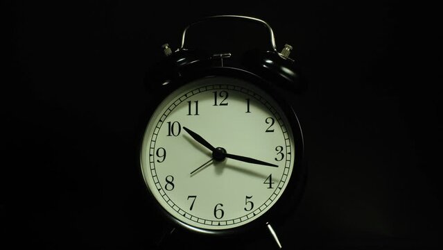 The alarm clock on a black background, in the style of time-lapse video.