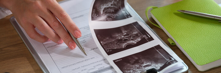 Female doctor analyzes results of patient's medical examination at her desk in clinic.