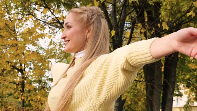 Autumn time. Welcome autumn concept image with overjoyed happy woman raising arms and closing eyes hugging and loving nature around. Outdoor people leisure activity concept. Freedom and success day. 