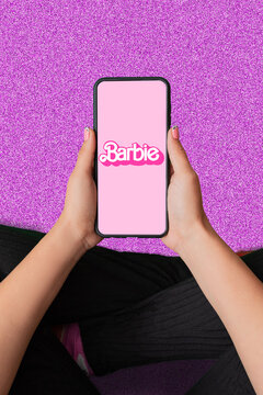 Buenos Aires, Argentina; 08-03-2023: Barbie the movie. Thematic vertical background of woman's hands holding a cell phone that represents the success and fury for the Barbie movie.