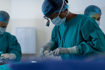 Diverse surgeons wearing surgical gowns operating on patient in operating theatre at hospital