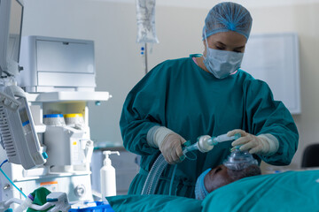 Caucasian female surgeon placing anaesthetic face mask on patient in operating theatre at hospital