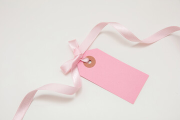 Blank pink price tag isolated on white background. Pastel color empty gift card and curly ribbon bow,