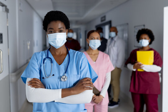 Portrait of diverse female doctors wearing face masks in corridor at hospital