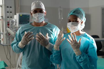 Portrait of diverse surgeons wearing surgical gowns in operating theatre at hospital