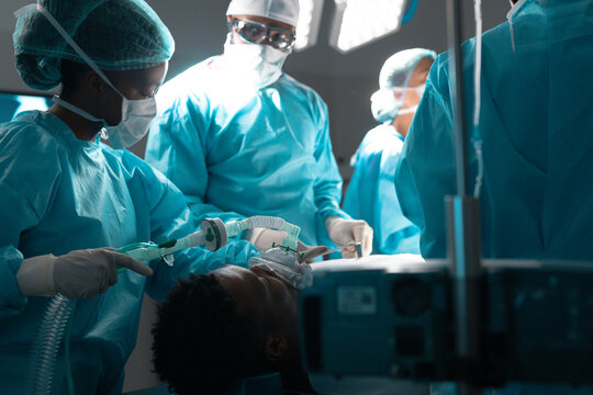 Diverse surgeons wearing surgical gowns operating on patient in operating theatre at hospital