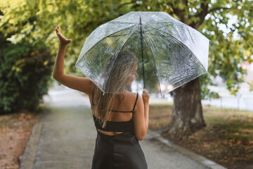 cheerful woman with umbrella checks the rain