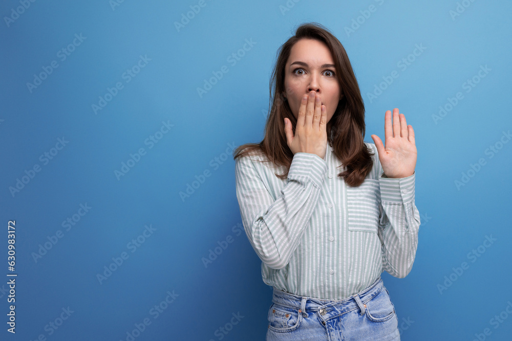 Poster shocked surprised young brunette woman in shirt on studio background