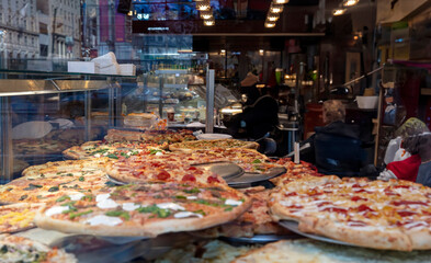 Pizza assortment in a shop display, closeup. Delicious Italian street food.