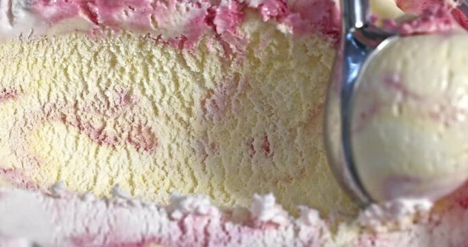 cranberry, mascarpone and vanilla ice cream scooping out of container by metal spoon